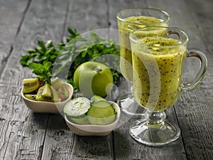 Freshly prepared smoothie of kiwi, Apple, parsley and cucumber and kiwi slices on the rustic table. Healthy and