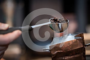 Freshly roasted coffee beans in an espresso fliter in a man`s hand