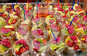 Freshly sliced fruit mixture in plastic cups on display