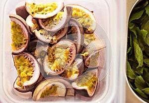 Freshly Sliced Passionfruit in a plastic tub next to mint