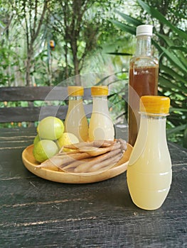 Freshly squeezed galingale juice in a plastic bottle placed on a brown wooden plate