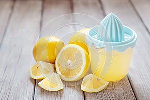 Freshly squeezed lemon juice with juicer on wooden table, copy space