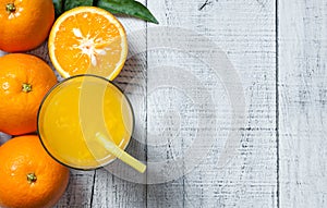 Freshly squeezed orange juice in glass with orange fruits on wooden background