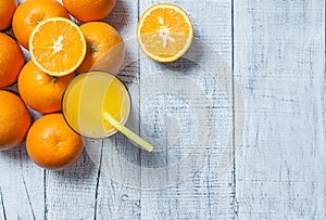 Freshly squeezed orange juice in glass with orange fruits on wooden background