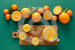 Freshly squeezed orange juice in a glass pitcher and fresh fruits with leaves, healthy drink, vitamin c concept, overhead view