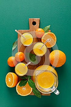 Freshly squeezed orange juice in a glass pitcher and fresh fruits with leaves, healthy drink, vitamin c concept, overhead view