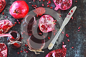 Freshly squeezed pomegranate juice in bottles and glasses. Ripe juicy pomegranates on the stylish shabby surface.