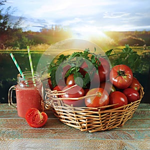 Freshly squeezed tomato juice in a glass cup, a basket with ripe tomatoes