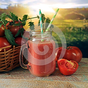 Freshly squeezed tomato juice in a glass cup, a basket with ripe tomatoes