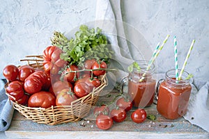 Freshly squeezed tomato juice in a glass cup and ripe tomatoes in a basket