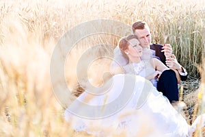 Freshly wed bride and groom posing in wheat field.