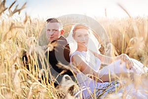Freshly wed bride and groom posing in wheat field.