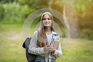 Freshman Girl. Beautiful Female College Student With Workbooks And Backpack Posing Outdoors photo