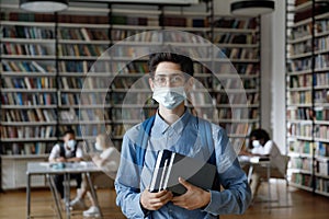 Freshman student in medical protective mask and backpack visiting library