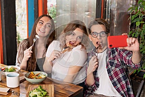 Freshmen in a cafe take a selfie. Teenage friends meeting for lunch. First year students spend leisure time together.