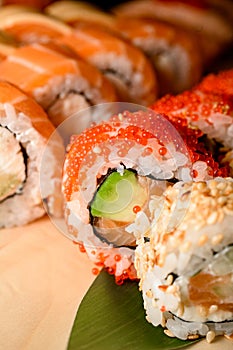 Freshness sushi with salmon and avocado decorated with red caviar on a wooden stand
