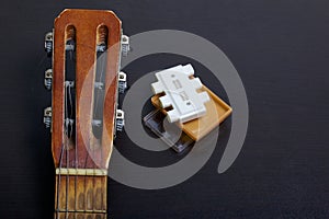 The fretboard of the acoustic guitar and the tuning fork to adjust it. On a dark background.