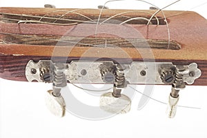 Fretboard with pegs of an old red wooden guitar with strings close-up isolated on a white background