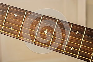 Fretboard and strings of a brown wooden guitar a close up