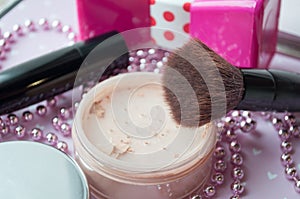 friable powder and brush, lipstick on a pink texture background