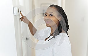 A frican woman lady adjusting the climate control panel on the wall wall thermostat