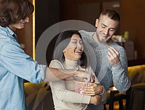 Friday evening. Joyful friends eating popcorn in cinema cafe