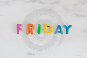 Friday word written with colorful letters on white marble stone background