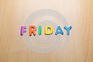 Friday word written with colorful letters on wooden table background