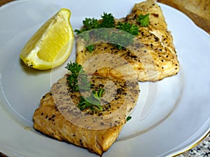 Fried arctic char trout fish fillets on white plate