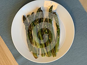 Fried asparagus in a white plate top view
