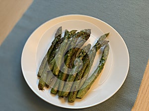 Fried asparagus in a white plate top view