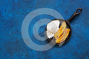Fried banana dessert with ice cream on a blue rustic background. Top view, flat lay, copy space