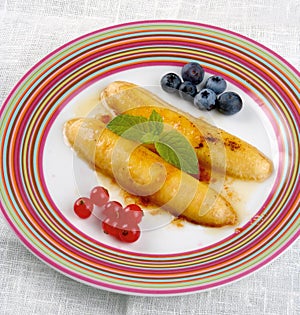 Fried banana flambe on a colorful plate with berries.