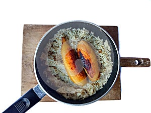 Fried bananas with rice on a pot with wooden board with white background. typical food of Guatemala
