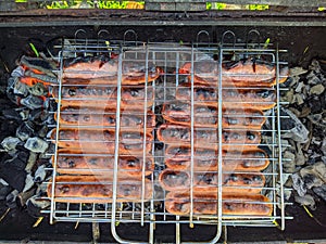 fried bbq sausages on the grill under hot coals top view