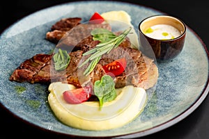 Fried beef mumm with mashed potatoes, served on a gray plate on a black background. photo