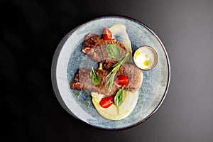 Fried beef mumm with mashed potatoes, served on a gray plate on a black background. photo