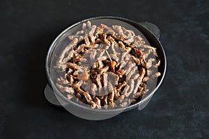 Fried beef in a pan on black table. Preparation for beef stroganoff.