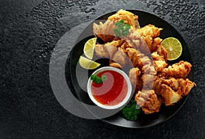 Fried Bloomin Onion with Chilli sauce and lime on black plate