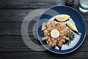 Fried blooming onion with dipping sauce served on dark wooden table, flat lay. Space for text