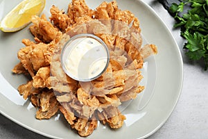 Fried blooming onion with dipping sauce served on grey table, flat lay