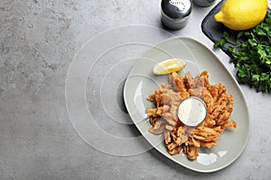 Fried blooming onion with dipping sauce served on grey table, flat lay. Space for text