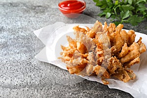 Fried blooming onion with dipping sauce served on grey table. Space for text