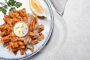 Fried blooming onion with dipping sauce served on light marble table, top view. Space for text