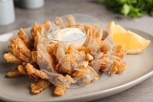 Fried blooming onion with dipping sauce served on table, closeup