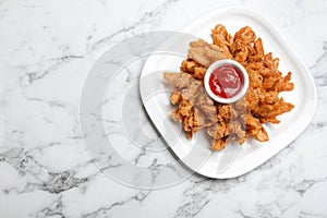 Fried blooming onion with dipping sauce served on white marble table, top view. Space for text