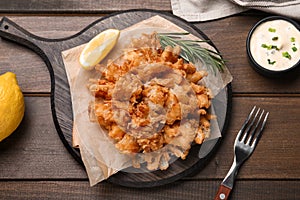 Fried blooming onion with dipping sauce served on wooden table, flat lay