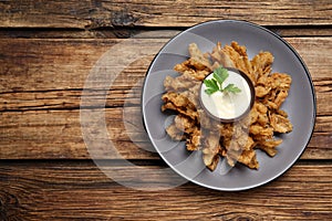 Fried blooming onion with dipping sauce served on wooden table, top view. Space for text