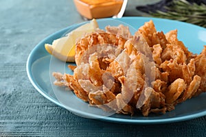 Fried blooming onion served on blue wooden table, closeup