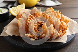 Fried blooming onion served on wooden table, closeup